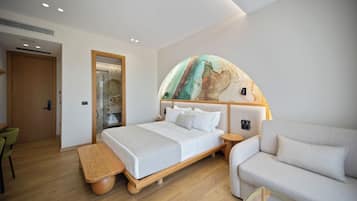 A modern hotel room with a large bed, a sofa, a wooden bench, and a glass coffee table.