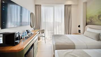 A hotel room with a bed, a desk with a telephone, a television, and a window with curtains.