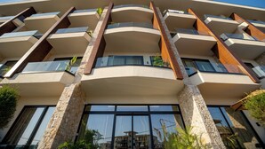 Un edificio de varios pisos con un diseño arquitectónico moderno, que presenta balcones y ventanas amplias.