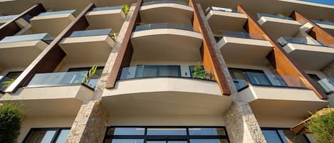 Un immeuble à plusieurs étages doté d’une architecture moderne, avec des balcons et de grandes fenêtres.