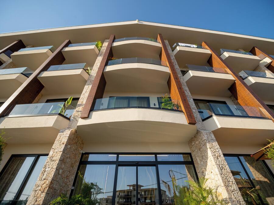 A multi-story building with a modern architectural design, featuring balconies and large windows.