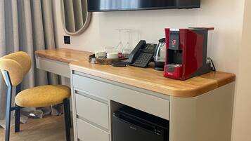 Cocina compacta con cafetera, teléfono y refrigerador pequeño.