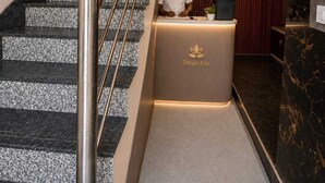 A reception desk with a clock, a reception sign, and a staircase with a metal railing. - Hotel Smile Inn-Next Railway Station (Bhubaneshwar)