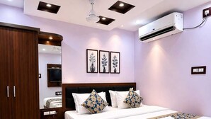 A hotel room with a large bed, a wardrobe, a mirror, a ceiling fan, and an air conditioning unit. - Hotel Smile Inn-Next Railway Station (Bhubaneshwar)