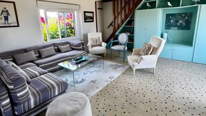 A living room with a sofa, armchairs, a coffee table, and a staircase.