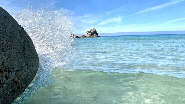 A clear view of a rocky coastline with waves crashing against the shore.