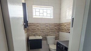 Ein kleines Badezimmer mit Toilette, Waschbecken und Waschmaschine.