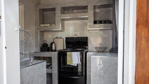 Eine kleine Küche mit integriertem Backofen, Wasserkocher und Geschirrgestell.