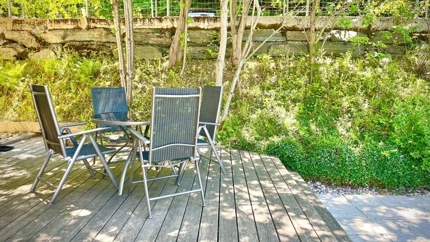 A wooden deck with metal chairs and a stone wall in the background. - Velden Pool Apartment - Large apartment with a private pool (Velden am Wörthersee)