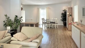 A modern living room with a sofa, dining table, chairs, and a kitchen area with cabinets and a countertop. - Velden Pool Apartment - Large apartment with a private pool (Velden am Wörthersee)