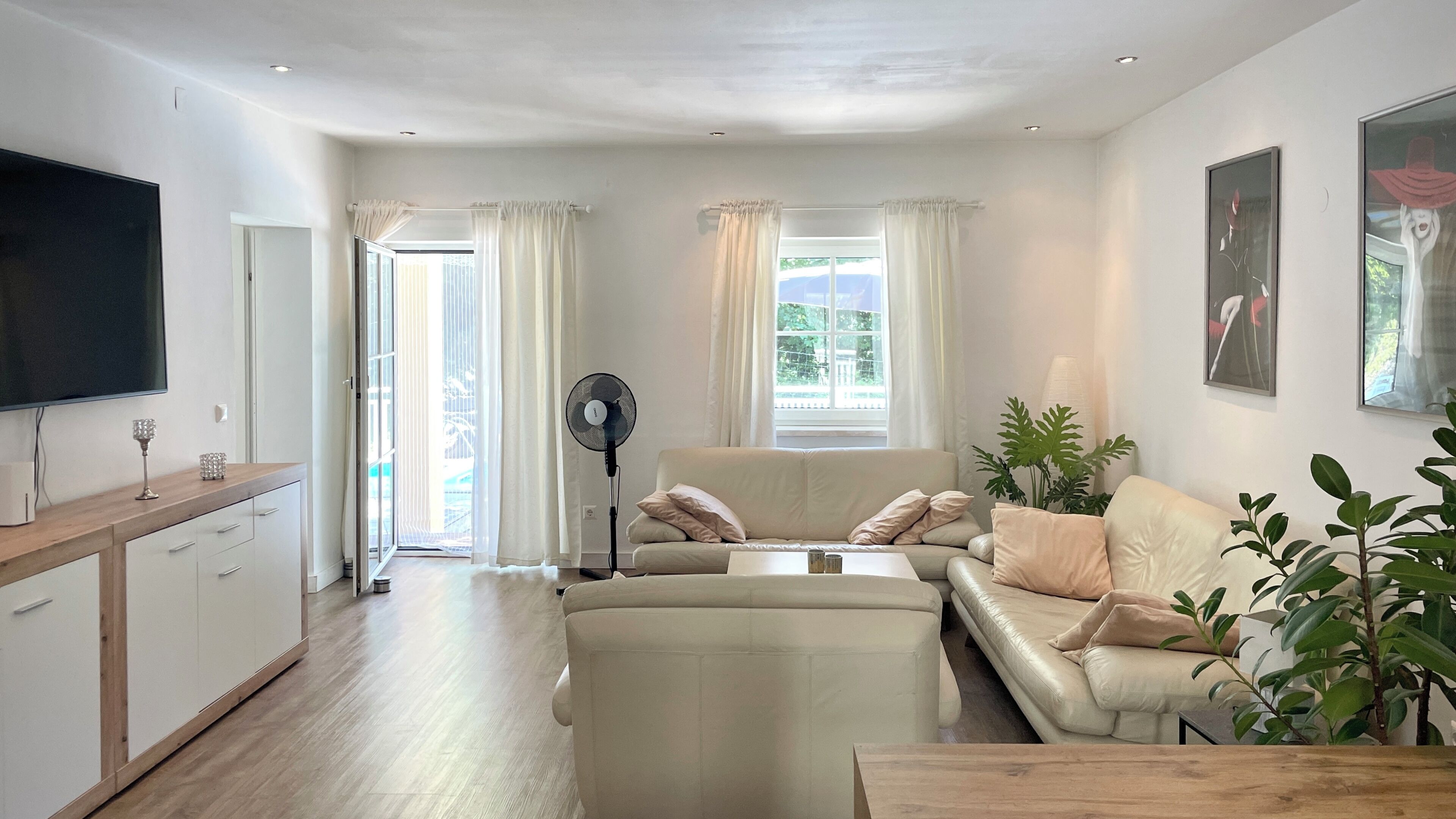 Un salon moderne avec un canapé, une table basse, un téléviseur et un ventilateur.