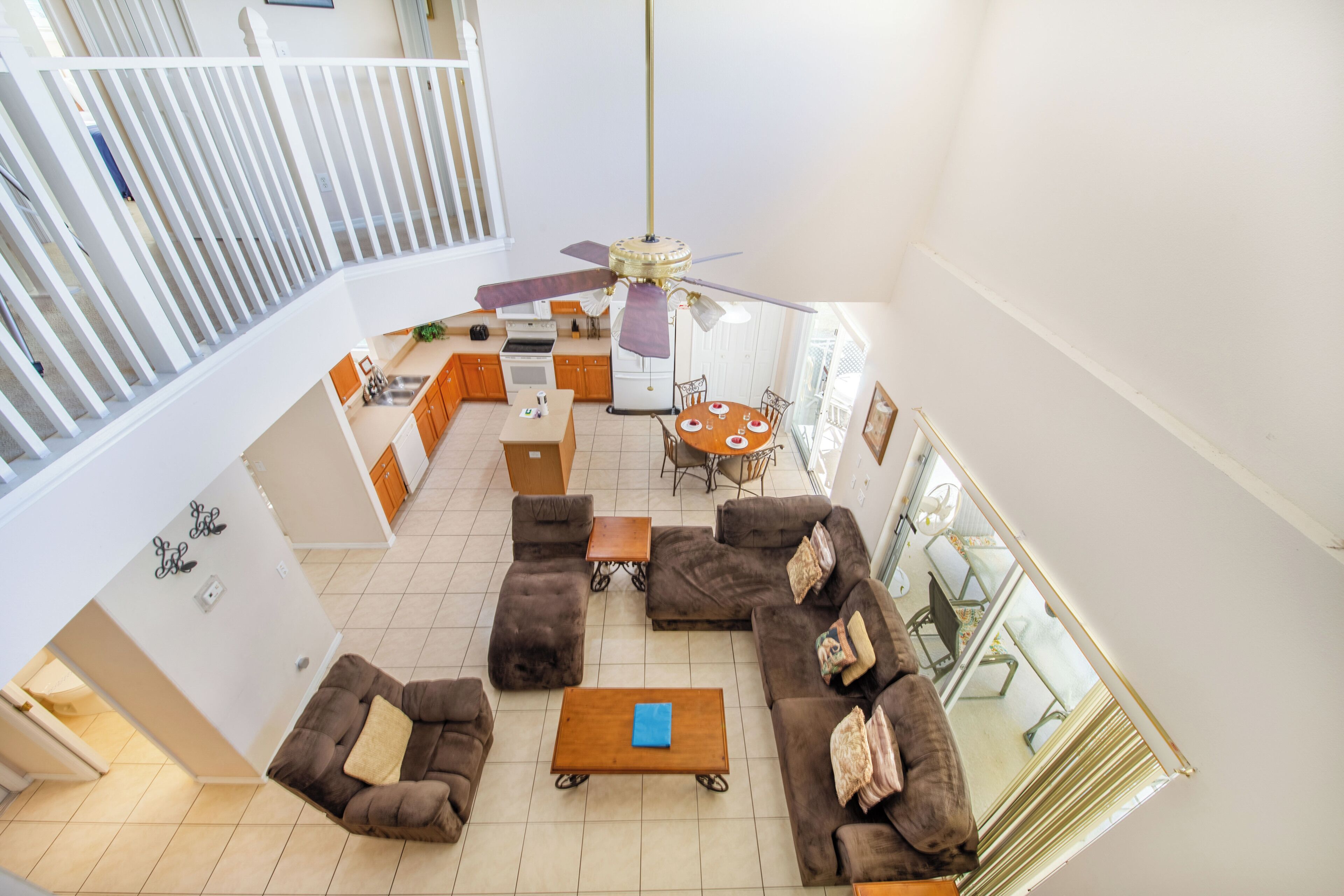 A spacious living area with a high ceiling, a dining table, and a kitchen in the background.