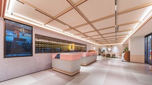 A modern lobby with a reception desk, a large digital display, and a seating area.