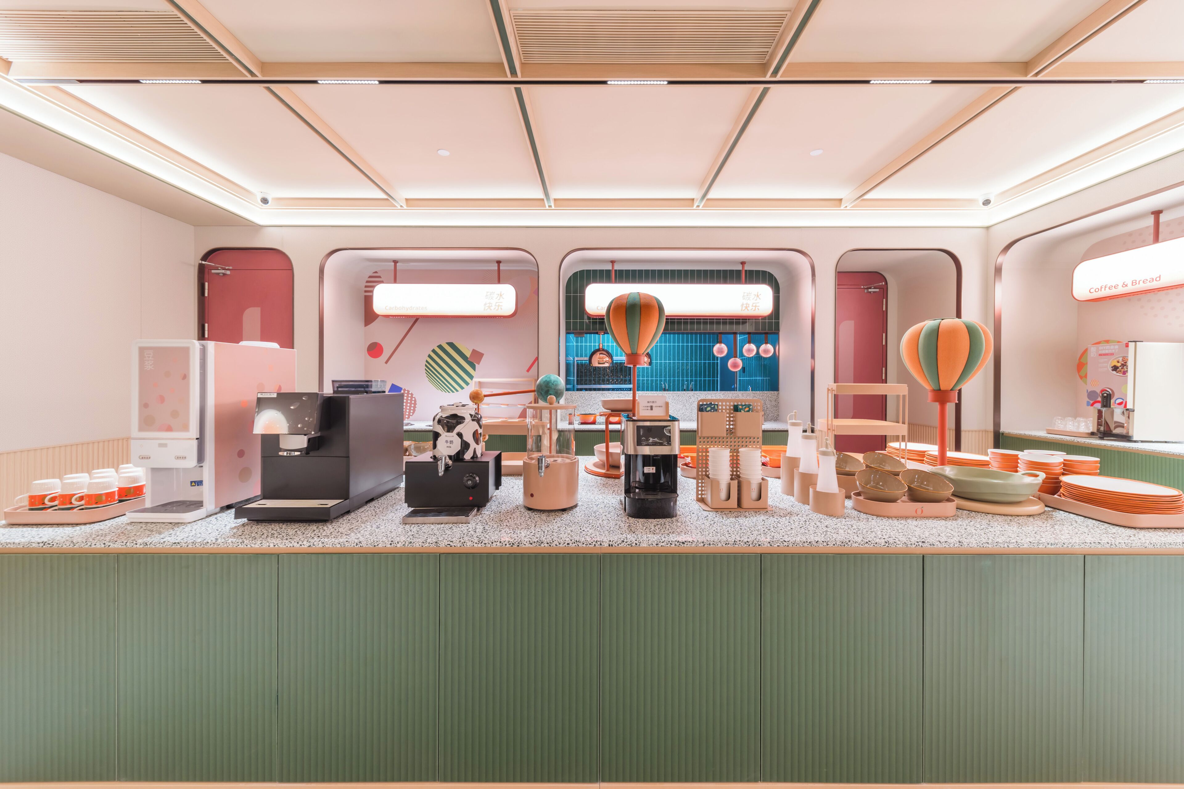 A modern interior with a counter displaying various items, a coffee station, and a view through a window.