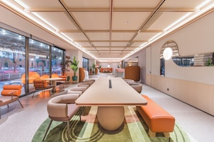 Un salón de conferencias moderno con una larga mesa, asientos cómodos, ventanas grandes y vistas al exterior.