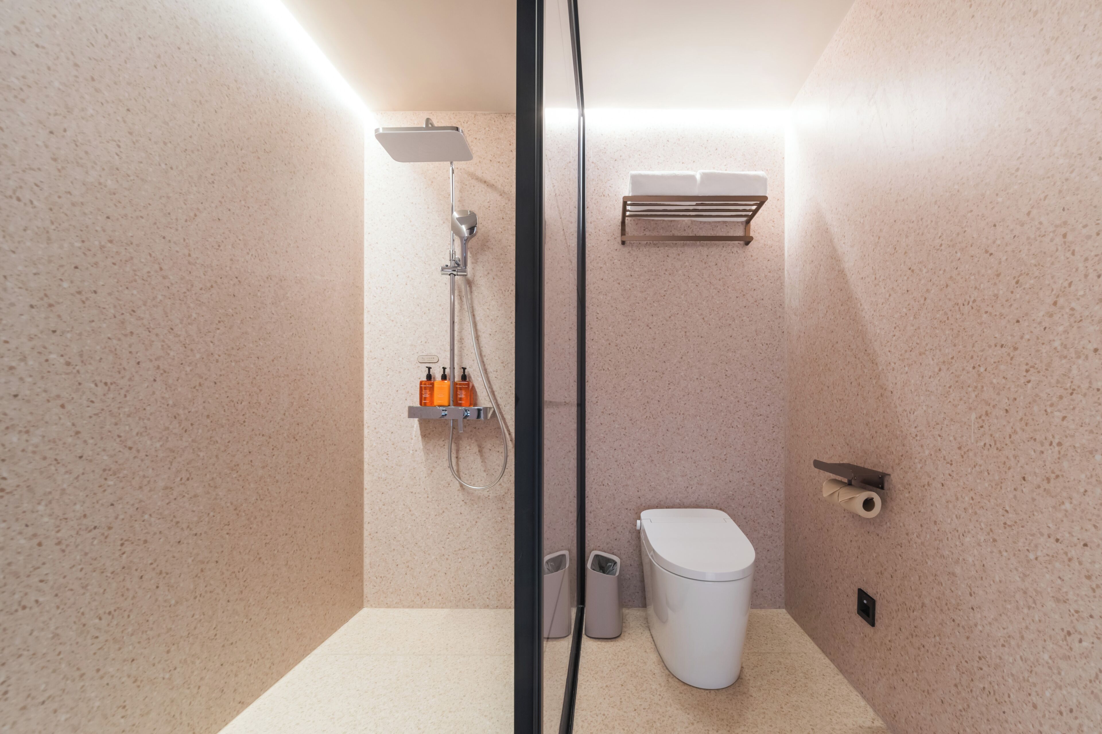 Un baño moderno con ducha, inodoro y estante de almacenamiento.