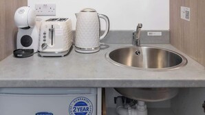 A kitchenette with a Bosch microwave, a coffee maker, a toaster, a kettle, and a sink. - Beautiful-Cosy-King Bed-Studio perfect for couples (Greater London)
