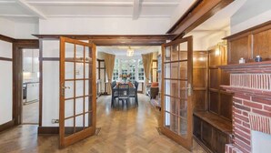 Um corredor com piso de madeira, uma sala de jantar com mesa e cadeiras, e uma lareira.