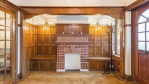 Quarto com lareira de tijolos, lambris de madeira e um banco.