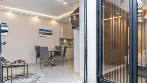 Ein modernes Interieur mit Essbereich, Küche und einer großen Glasschiebetür, die zu einem Außenbereich führt.