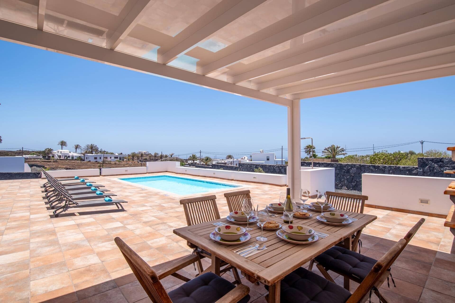 A rooftop terrace with a swimming pool, outdoor seating, and a clear view of the surrounding landscape.
