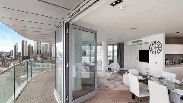 A modern apartment with a balcony, a dining area, and a kitchen. - Exclusive London Penthouse with River Views (Greater London)