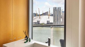 A bathroom with a window view of a construction site and a river. - Exclusive London Penthouse with River Views (Greater London)