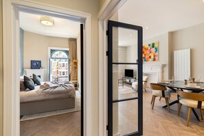 Un interior moderno con zona de comedor, sofá con cojines, chimenea y un ventanal grande.
