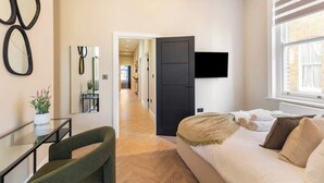 Een slaapkamer met een bed, een televisie, een bureau en een stoel.
