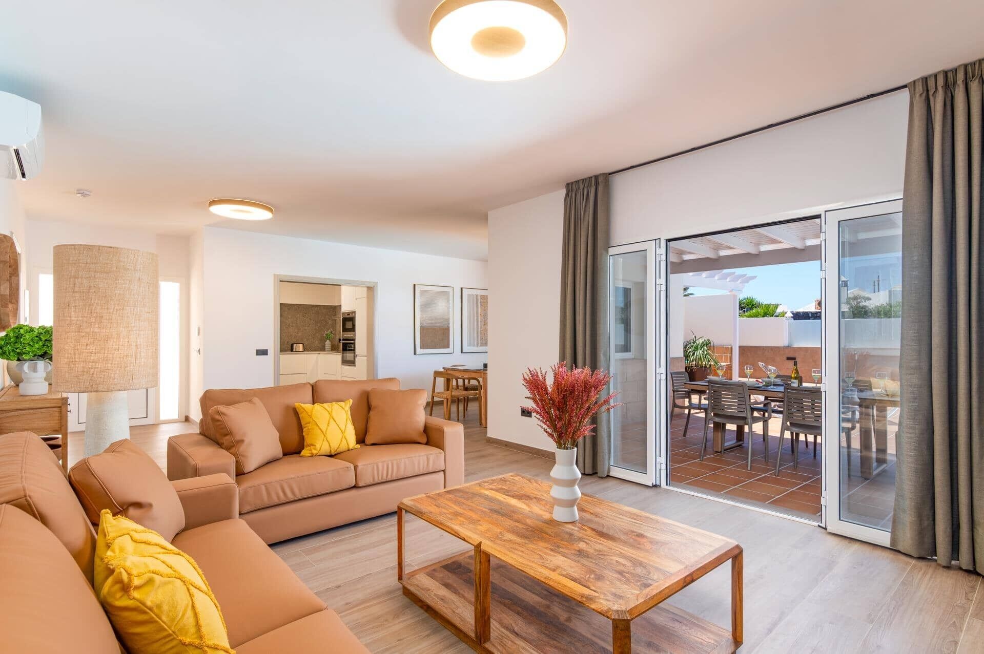 A modern living room with a sofa, coffee table, and a view to an outdoor patio area.