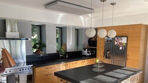 Una cocina moderna con una isla central, electrodomésticos de acero inoxidable, armarios de madera y un ventanal grande.