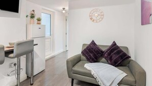 Un espacio moderno para la vida con un sofá, un taburete de bar, un reloj en la pared y un televisor.