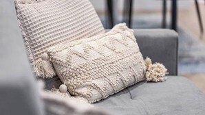 Un canapé gris agrémenté d’un plaid texturé et d’un coussin décoratif.