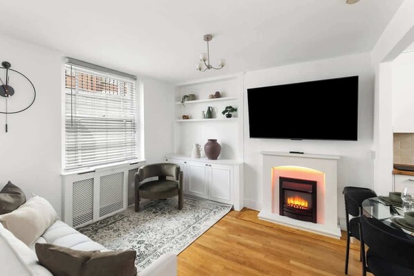 Ein modernes Wohnzimmer mit Kamin, Fernseher und Essbereich.