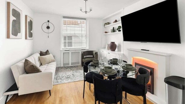 Ein modernes Wohnzimmer mit einer Couch, einem Esstisch, Stühlen, einem Kamin und einem Fernseher.