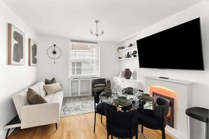 Ein modernes Wohnzimmer mit einer Couch, einem Esstisch, Stühlen, einem Kamin und einem Fernseher.