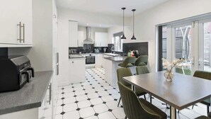Eine moderne Küche mit Essbereich, ausgestattet mit Grill, weißen Schränken und einem schwarz-weißen Fliesenboden.