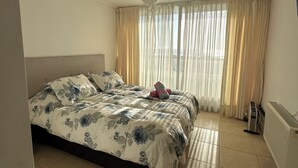 Ein Schlafzimmer mit Bett, Vorhängen, Heizkörper und Fenster.