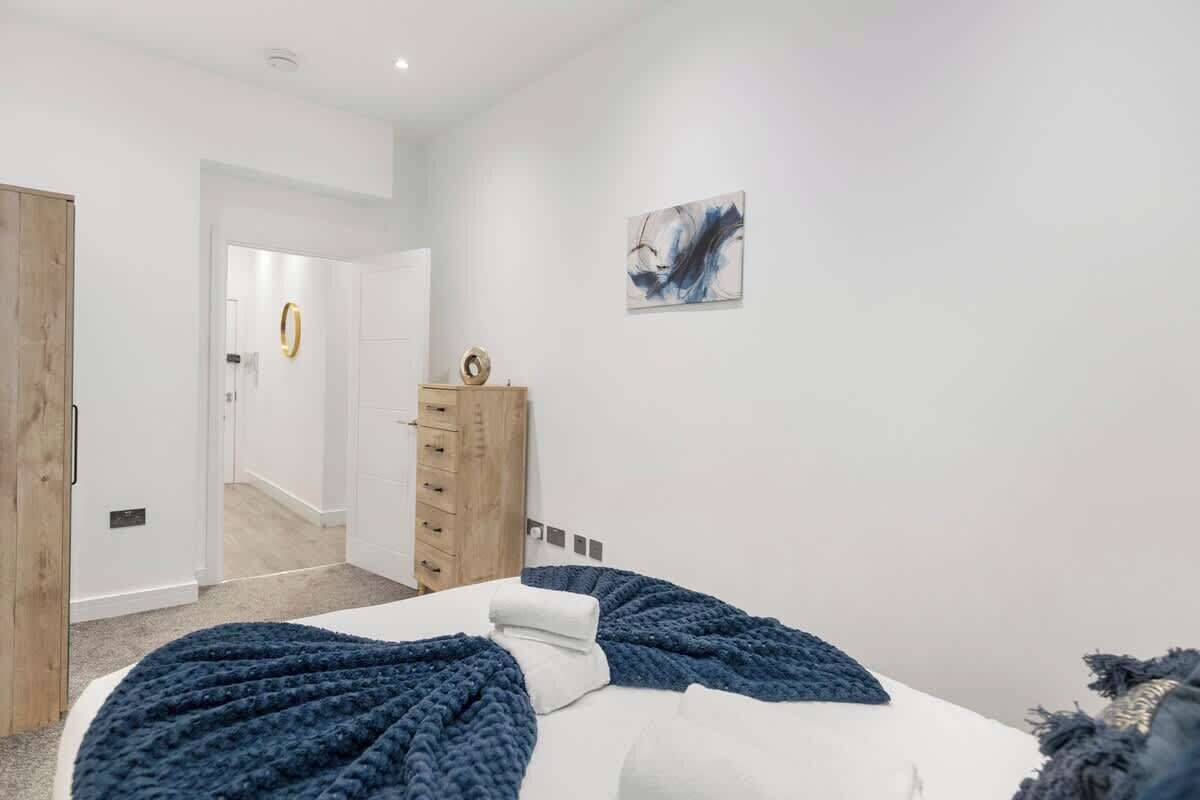 Un dormitorio con cama, cómoda, puerta y pared con un cuadro.