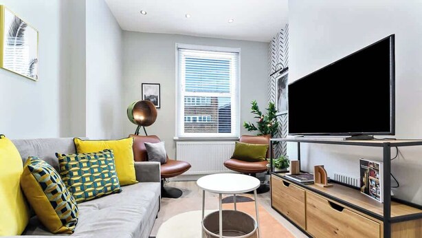 Ein modernes Wohnzimmer mit einer Couch, einem Couchtisch, einem Fernseher und einer Heizung.
