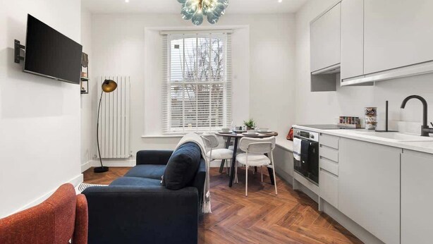Eine moderne Küche mit weißen Schränken, einem eingebauten Backofen und einem Essbereich mit Tisch und Stühlen.