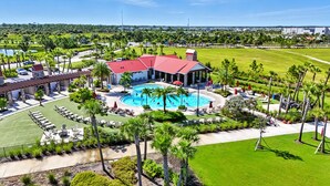 Een resort met een groot zwembad, terrasjes en een golfbaan op de achtergrond.