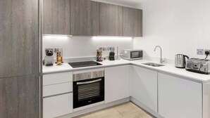 Una cocina moderna con armarios blancos, horno empotrado, microondas y tostadora.