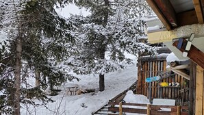 A wooden deck with a snow-covered railing, a table, and a bench.