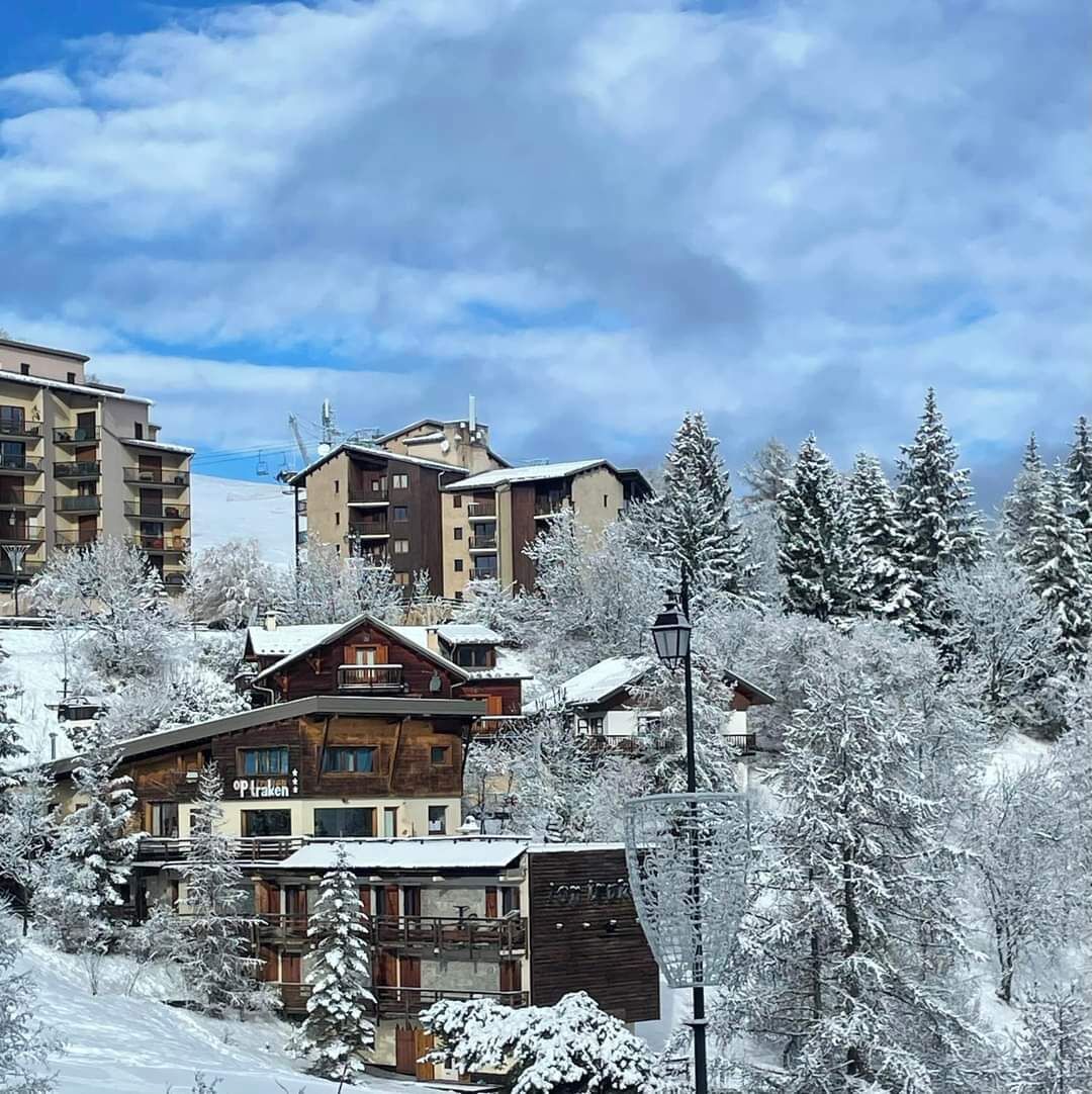 A snow-covered lodge with multiple floors, a ski lift in the background, and a snowy landscape.