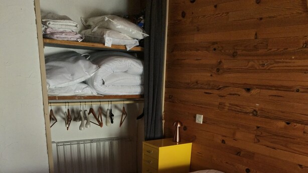 A bedroom with a bed, a wardrobe, and a wooden wall.