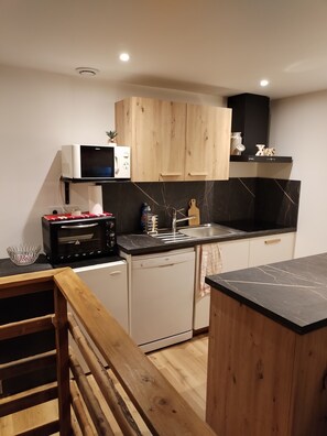 A compact kitchen with wooden cabinets, a microwave, a toaster, a sink, and a dishwasher.
