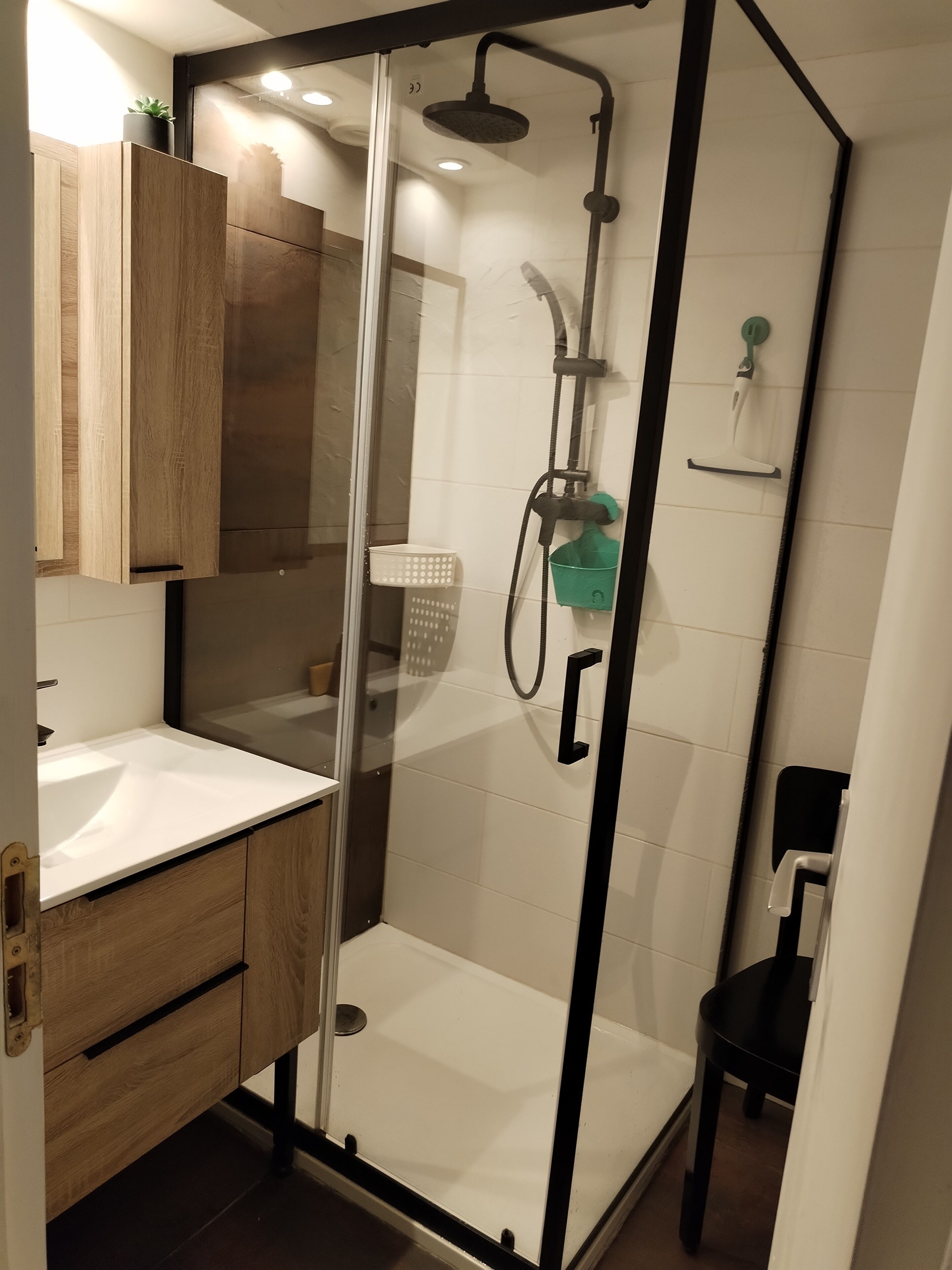 A modern bathroom with a glass-enclosed shower, a wooden vanity, and a white sink.