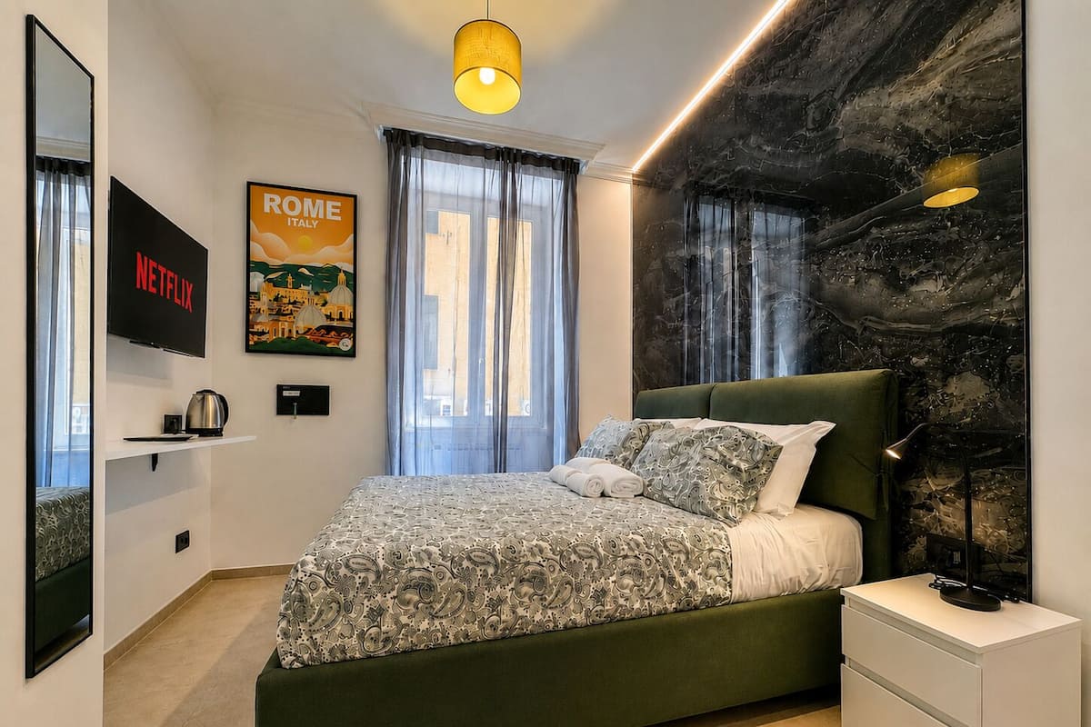 Un dormitorio moderno con una cama verde, un televisor de pantalla plana, un cartel de Roma, Italia, y una pared de mármol.
