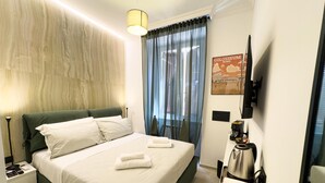 A hotel room with a bed, a nightstand, a coffee maker, and a poster of the Colosseum. - VATICAN ROOMS DORIA  (Rome)